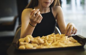 Close up of teenage girl eating french fries obesity concept