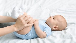 Mom doing gymnastics with her newborn child to relieve constipation