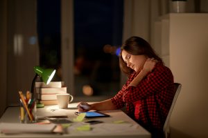 tired student or woman touching neck at night home