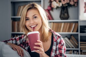 Blonde female drinks coffee.
