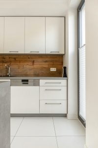 Real photo of an elegant, white kitchen interior with wooden pan