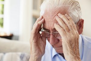 Senior Man Sitting On Sofa At Home Suffering From Depression