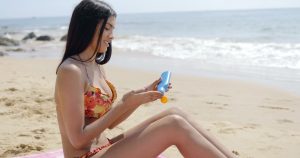 Woman applying cream on beach