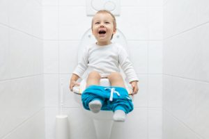 Adorable young child sitting on the toilet