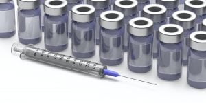 Injection syringe and vaccine vials on blue background