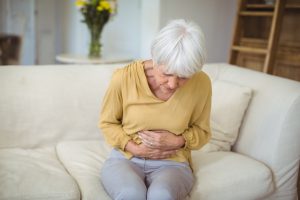 Senior woman suffering from stomach pain in living room