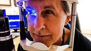 Active baby boomer having his eyes examined as a yearly eye checkup using medical equipment.