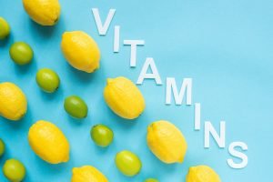 Flat Lay With Ripe Yellow Lemons, Green Limes And Word Vitamins on Blue Background